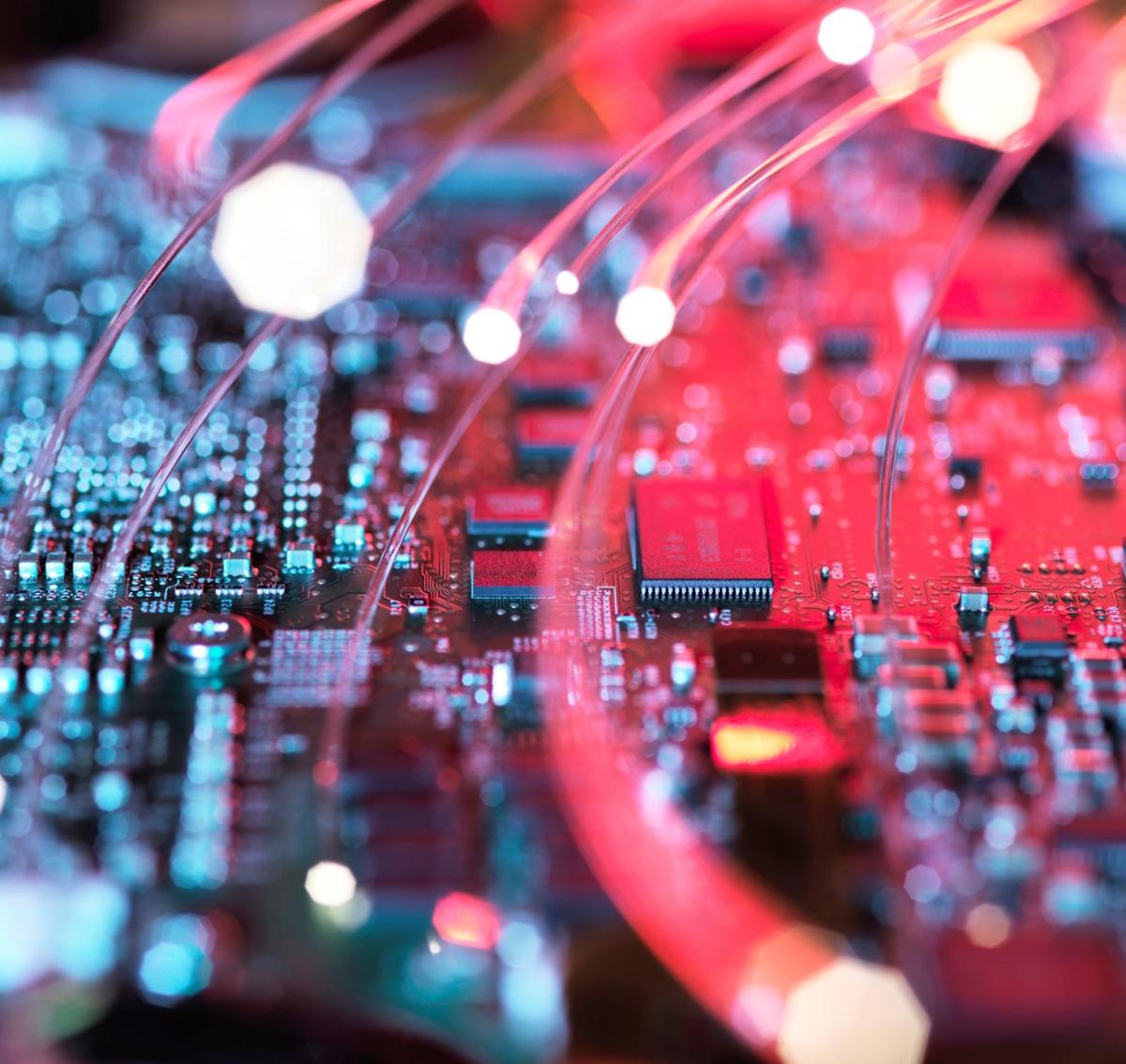 Motherboard shown with flashing lights and fiber optic cables artistically spread above it.
