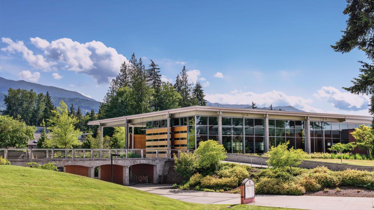 Peninsula College building with lush forested mountains behind.